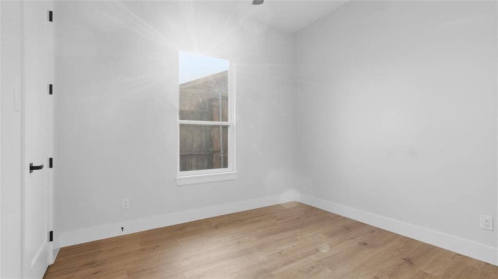 2816 Marburg Street, Dallas, TX 75215 Neutral interior room featuring wood-finish flooring, a single-hung window, and a door with matte black hardware