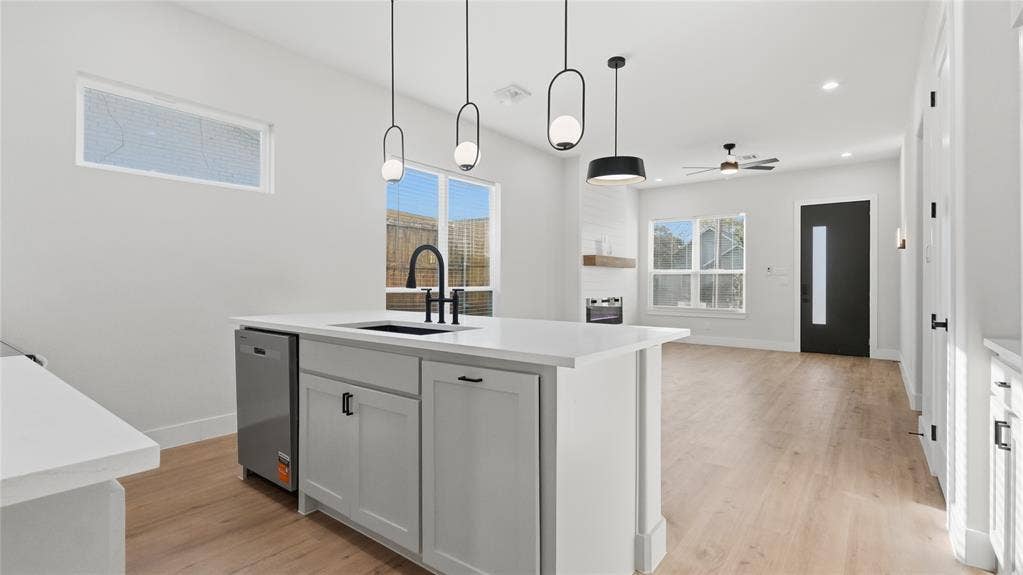 2816 Marburg Street, Dallas, TX 75215 Kitchen island featuring a stone-surface countertop, an integrated sink with a matte black faucet, and pendant lighting