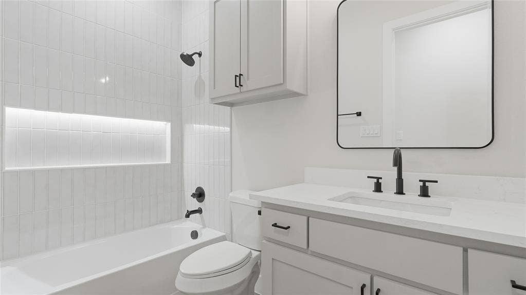 2816 Marburg Street, Dallas, TX 75215 Bathroom featuring a vanity with a white countertop and rectangular undermount sink, matte black hardware, vertical tile surround with built-in recessed shelving, a wall-mounted medicine cabinet, and a rounded rectangular mirror