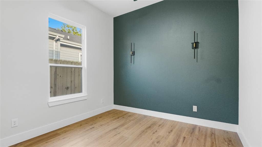 2816 Marburg Street, Dallas, TX 75215 Room featuring wood-finish flooring, a painted accent wall, and two built-in wall-mounted light fixtures