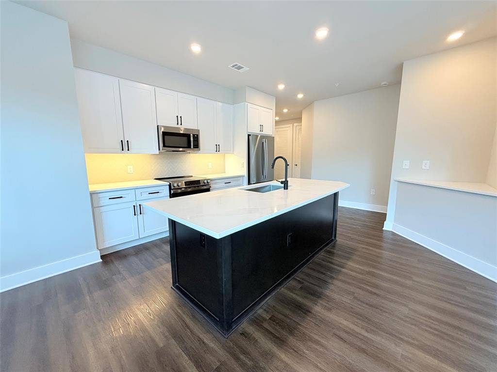 3255 Carlisle Street, #1207, Dallas, TX 75204 Kitchen with white cabinets, dark cabinets, recessed lighting, a center island with sink, and stainless steel appliances