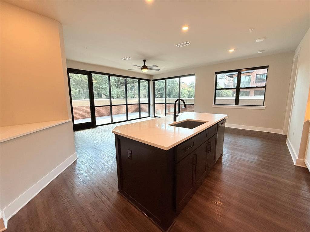 3255 Carlisle Street, #1207, Dallas, TX 75204 Kitchen with dark wood-type flooring, recessed lighting, an island with sink, a ceiling fan, and open floor plan
