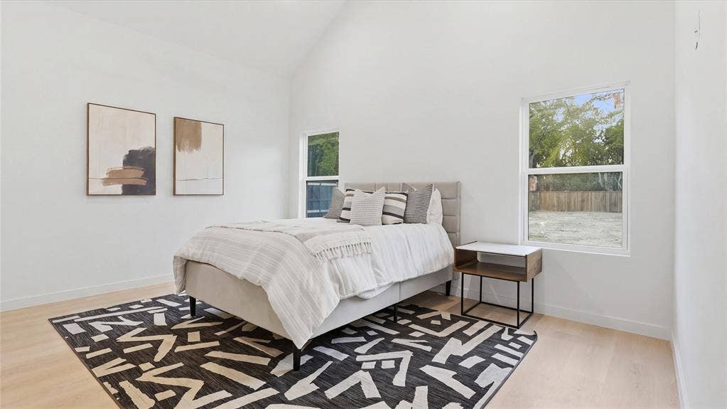 High vaulted ceiling, wood-finish flooring, and natural light provided by dual windows