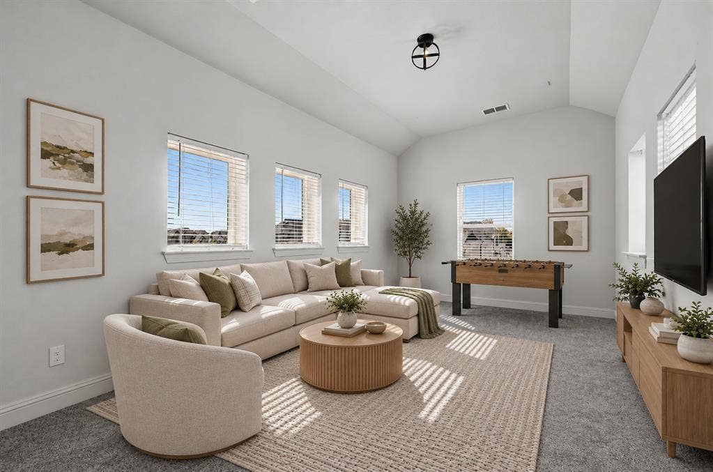 Vaulted ceilings, neutral wall color palette, carpeted flooring, and multiple windows with horizontal blinds
