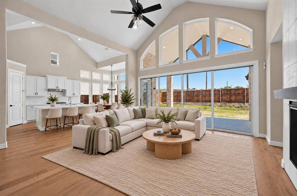 Vaulted ceiling, wood-finish flooring, floor-to-ceiling multi-panel sliding glass doors, arched clerestory windows, and white cabinetry