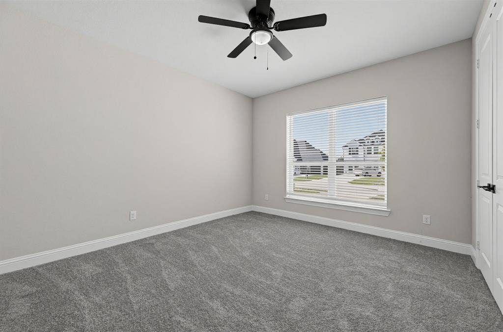 Neutral wall finishes, plush wall-to-wall carpeting, matte black ceiling fan with integrated lighting, and white six-panel closet doors
