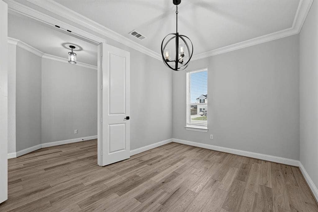 Interior room featuring wood-finish flooring, crown molding, a spherical metal chandelier, and a single-panel interior door
