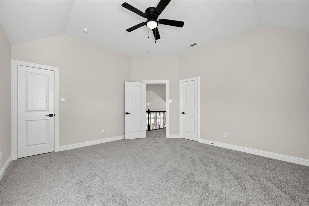 Vaulted ceilings, carpeted flooring, matte black hardware, three-panel interior doors, and a ceiling fan with integrated lighting
