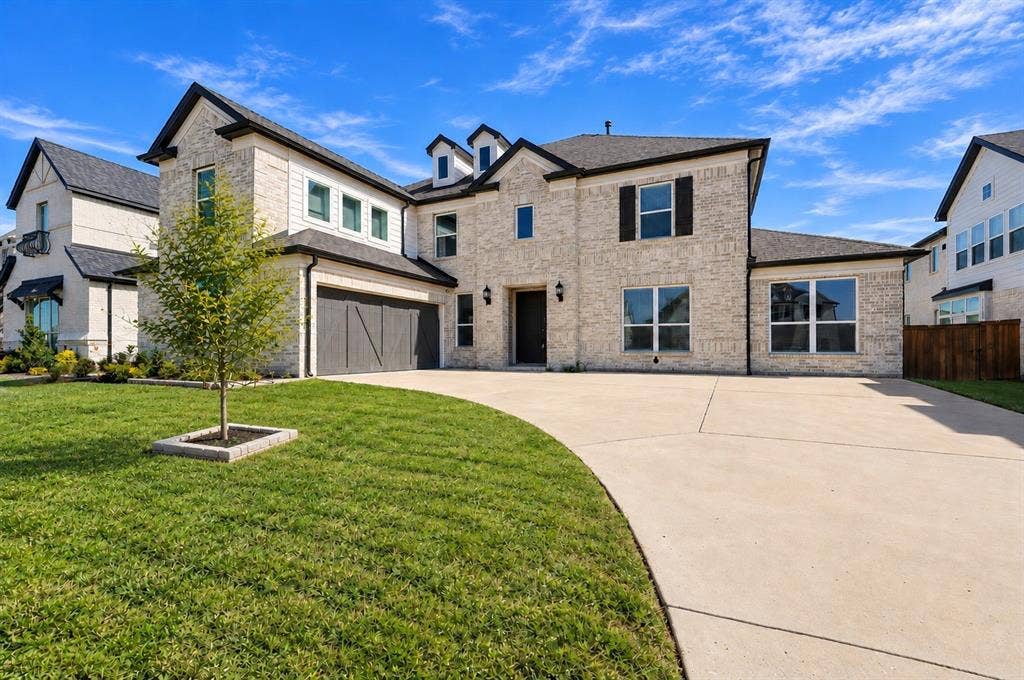 Two-story brick and siding exterior featuring a multi-gabled roofline, concrete driveway, attached multi-car garage, and dormer windows