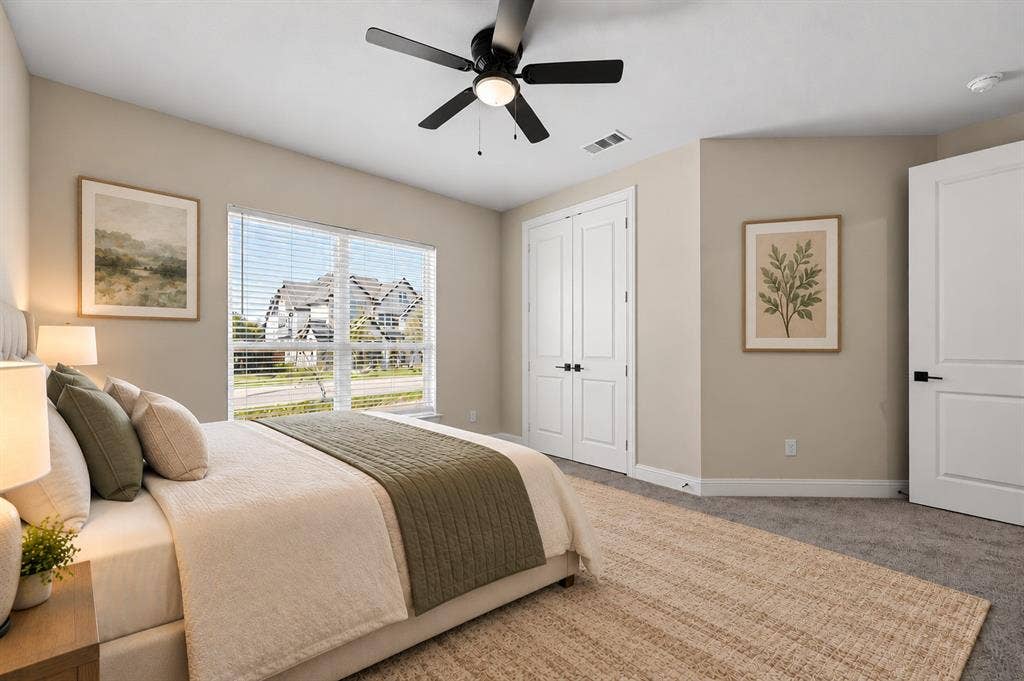Neutral-toned room featuring a central ceiling fan with an integrated light fixture, double-door closet, multi-pane window, and interior doors with matte black hardware