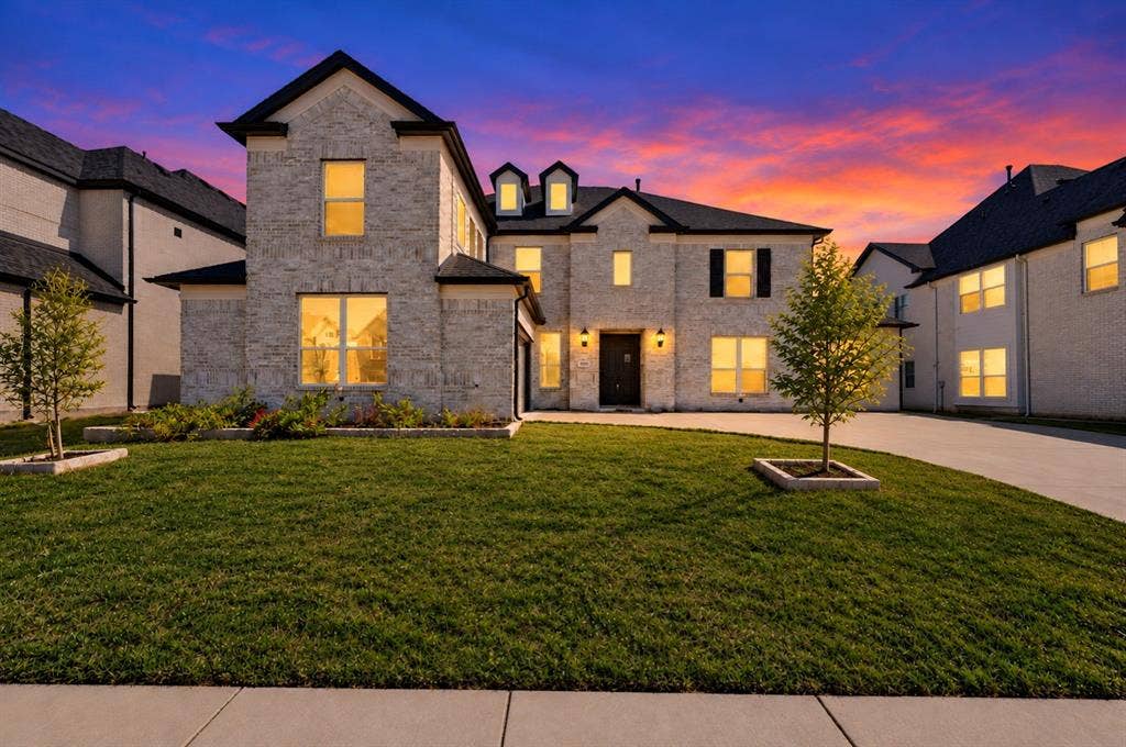 Multi-story brick exterior featuring a steep-pitched roofline, multi-pane windows, decorative dormers, and a paved concrete driveway