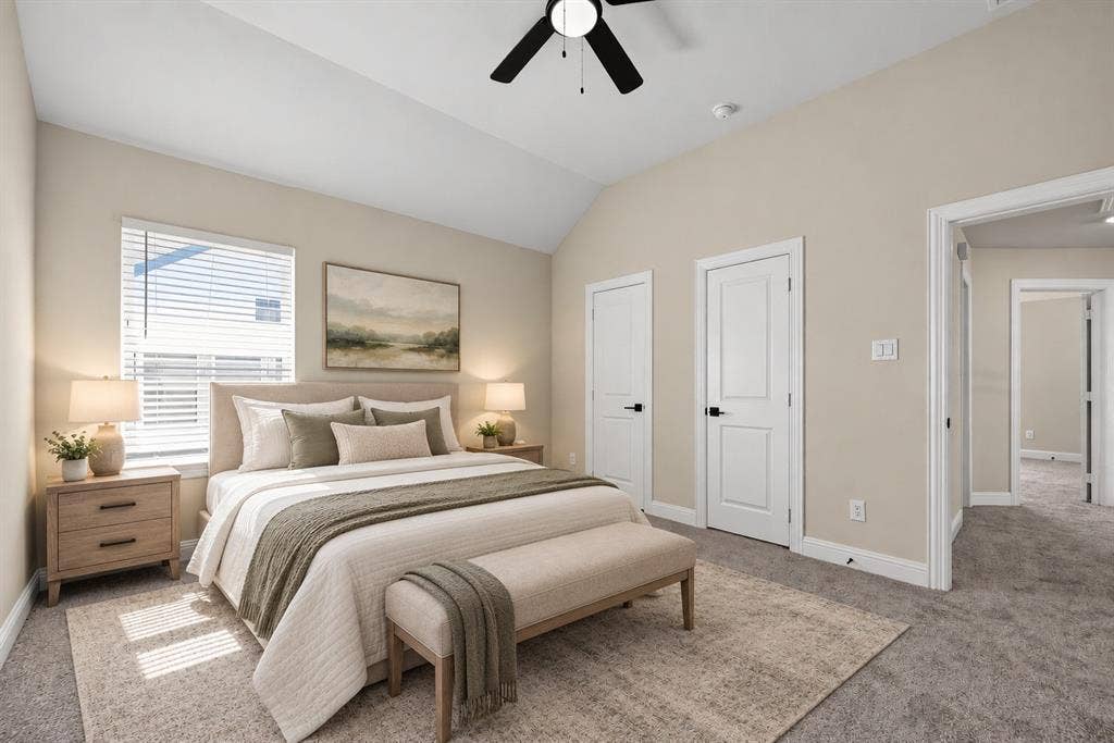 Vaulted ceiling featuring a central matte black ceiling fan, neutral wall tones, carpeted flooring, and white interior doors with matte black hardware
