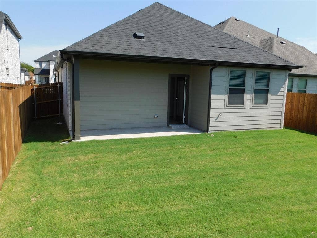 2702 Baynes Place, Princeton, TX 75407 Rear exterior featuring a covered concrete patio, horizontal siding, composition shingle roof, and a fenced backyard with a grass lawn
