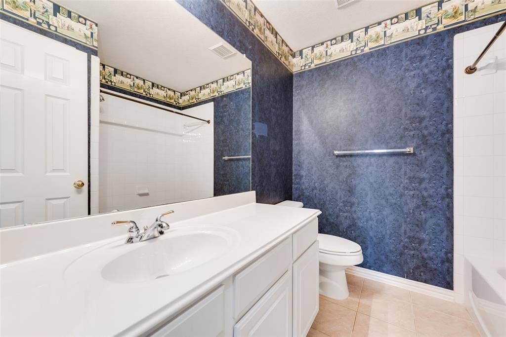 7900 Brookmount Street, Plano, TX 75024 Bathroom featuring a white vanity with an integrated sink, large wall-mounted mirror, ceramic tile flooring, and a tub-shower combination with a surround
