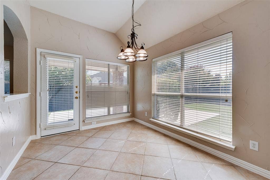7900 Brookmount Street, Plano, TX 75024 Vaulted ceiling with an iron chandelier, large windows with horizontal blinds, diagonal ceramic tile flooring, and a glass-paneled exterior door
