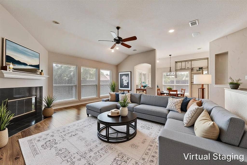7900 Brookmount Street, Plano, TX 75024 Living area with vaulted ceilings, wood-finish flooring, fireplace with a tiled surround, crown-molded mantel, and a ceiling fan