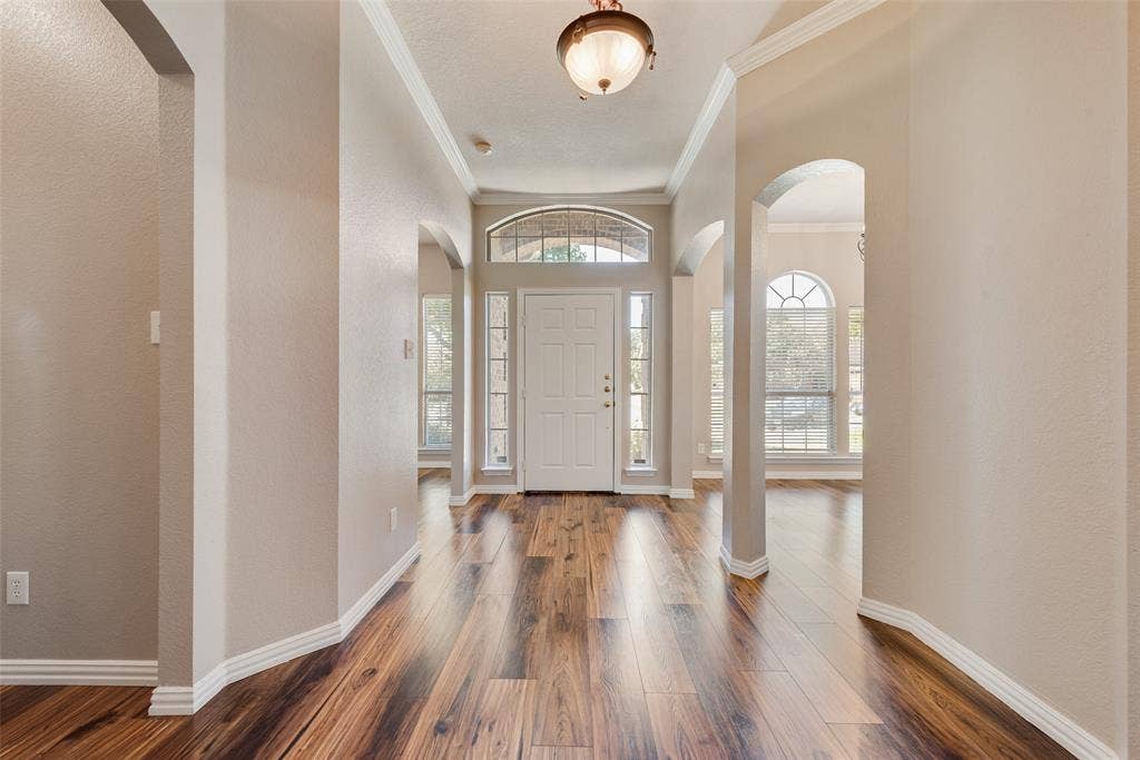 7900 Brookmount Street, Plano, TX 75024 Foyer featuring wood-finish flooring, arched entryways, multi-pane transom window, and a semi-flush mount light fixture