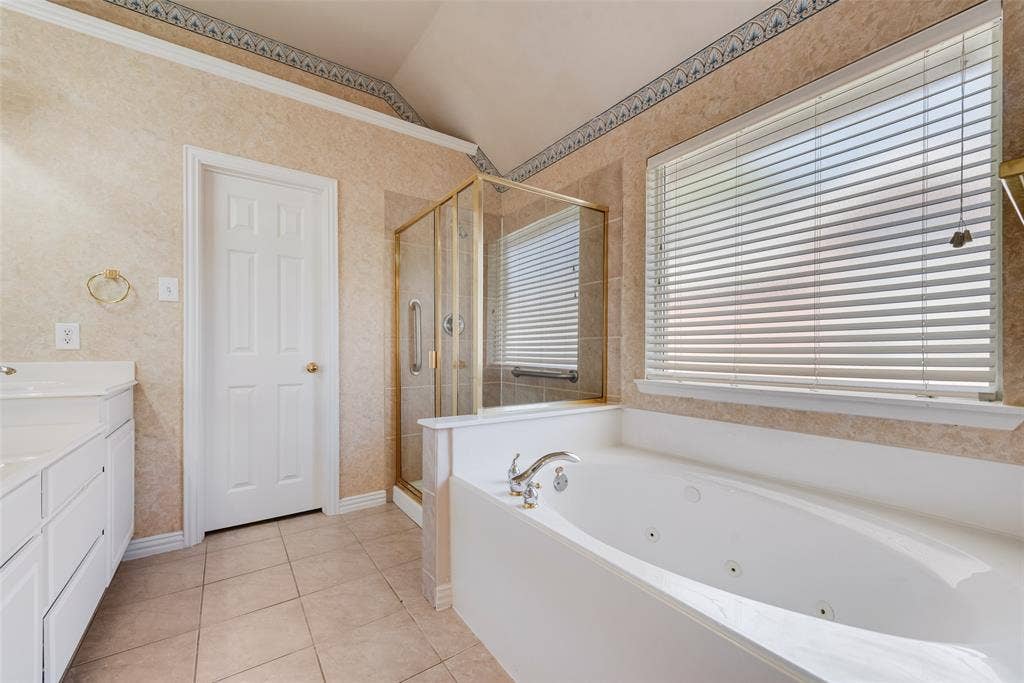 7900 Brookmount Street, Plano, TX 75024 Bathroom featuring a jetted soaking tub, glass-enclosed shower with gold-tone hardware, tile flooring, and vaulted ceiling