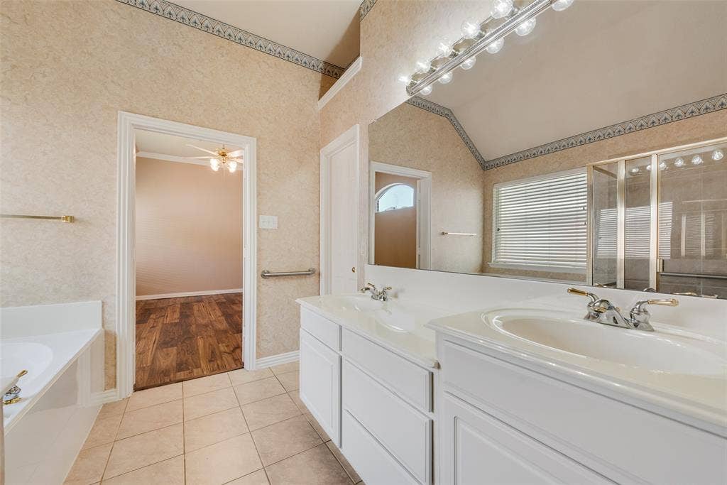 7900 Brookmount Street, Plano, TX 75024 Bathroom featuring a dual-sink vanity with white cabinetry, a full-width mirror, tile flooring, and a separate bathtub and glass-enclosed shower