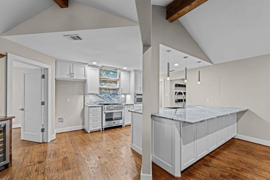 9656 Ravensway Drive, Dallas, TX 75238 The open kitchen features white cabinetry and a high-end stainless steel gas range
