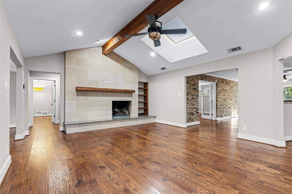 9656 Ravensway Drive, Dallas, TX 75238 Vaulted ceiling with exposed wood beam, stone-surround fireplace with wood mantel and a skylight