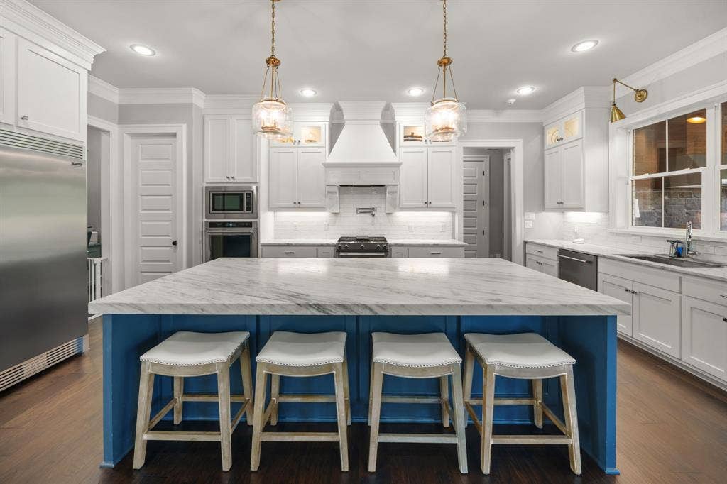 7609 Timber Trail, Tyler, TX 75703 Kitchen featuring a large central island with a stone countertop, white cabinetry with crown molding, stainless steel built-in appliances, recessed lighting, and wood-finish flooring