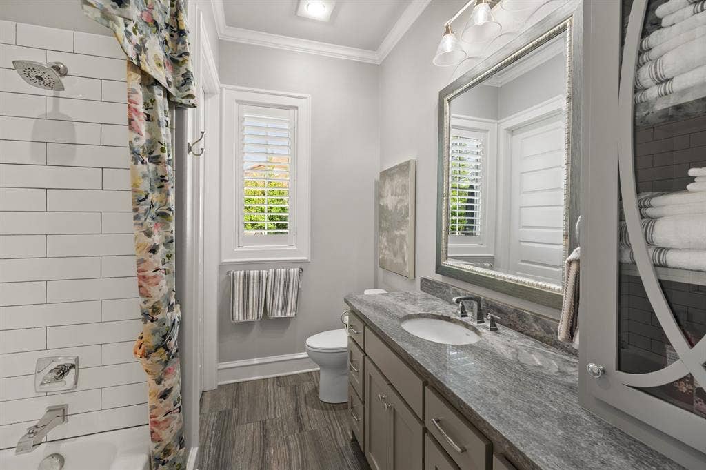 7609 Timber Trail, Tyler, TX 75703 Bathroom featuring a stone-surface vanity with an integrated sink, white subway tile shower surround, interior window shutters, and built-in cabinetry with decorative glass inlay