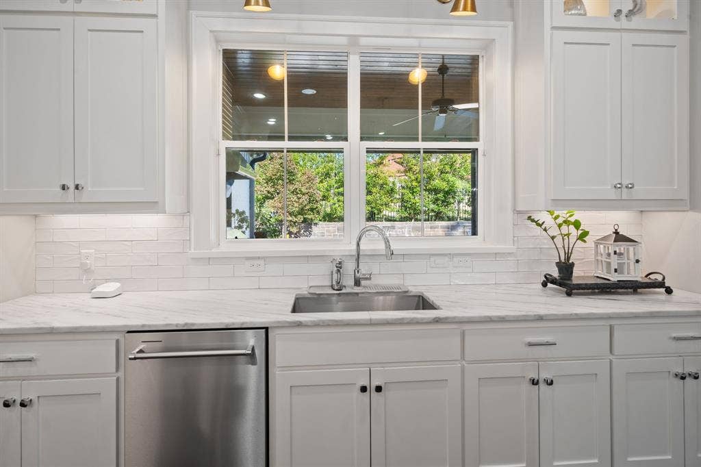 7609 Timber Trail, Tyler, TX 75703 Kitchen featuring white Shaker-style cabinetry, stone-patterned countertops, a white subway tile backsplash, stainless steel under-mount sink with a gooseneck faucet, and an integrated stainless steel dishwasher