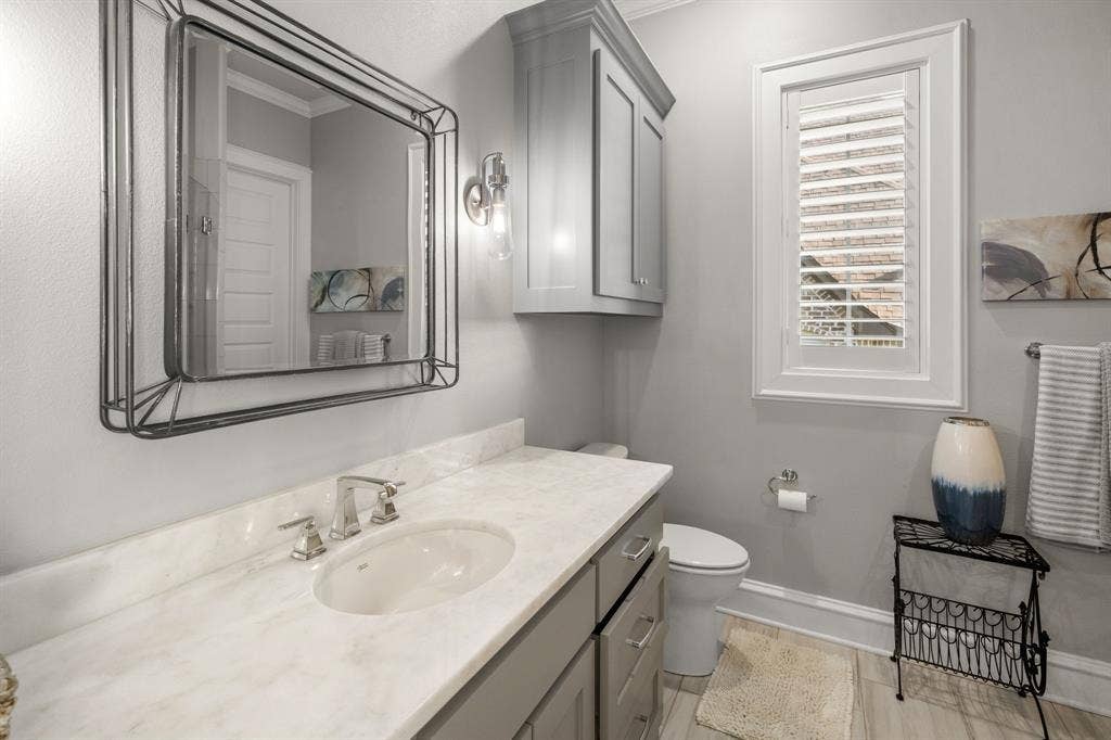 7609 Timber Trail, Tyler, TX 75703 Vanity featuring a light-toned countertop, undermount sink, and wall-mounted metallic light fixture