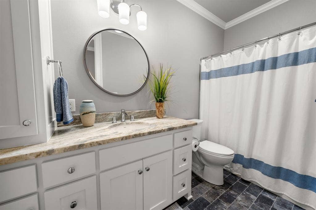7609 Timber Trail, Tyler, TX 75703 Bathroom featuring a white shaker-style vanity with stone-patterned countertop, integrated basin, round mirror, and tile flooring