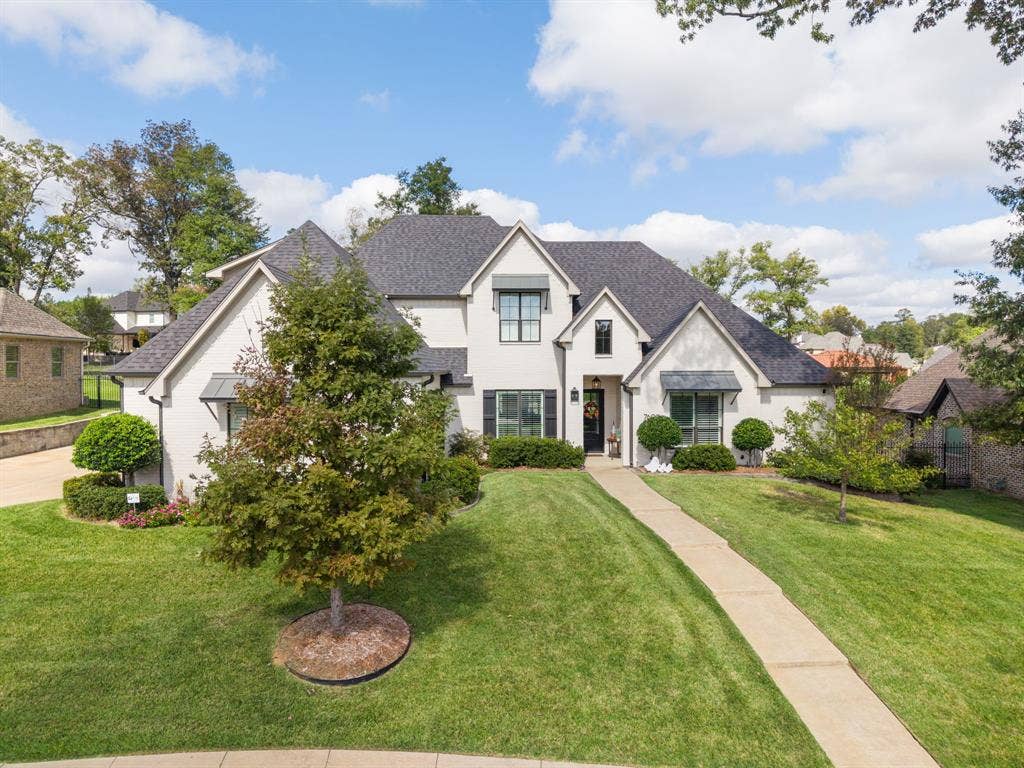 7609 Timber Trail, Tyler, TX 75703 Stucco exterior featuring multi-gabled rooflines, black metal awnings, grid-pattern windows, and a paved walkway