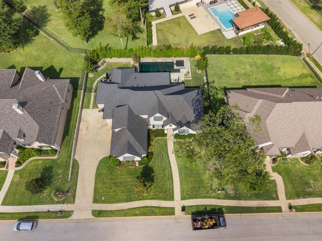 7609 Timber Trail, Tyler, TX 75703 Aerial perspective featuring a multi-gabled roofline, concrete driveway, stone-paved walkway, and a rectangular swimming pool with an integrated spa