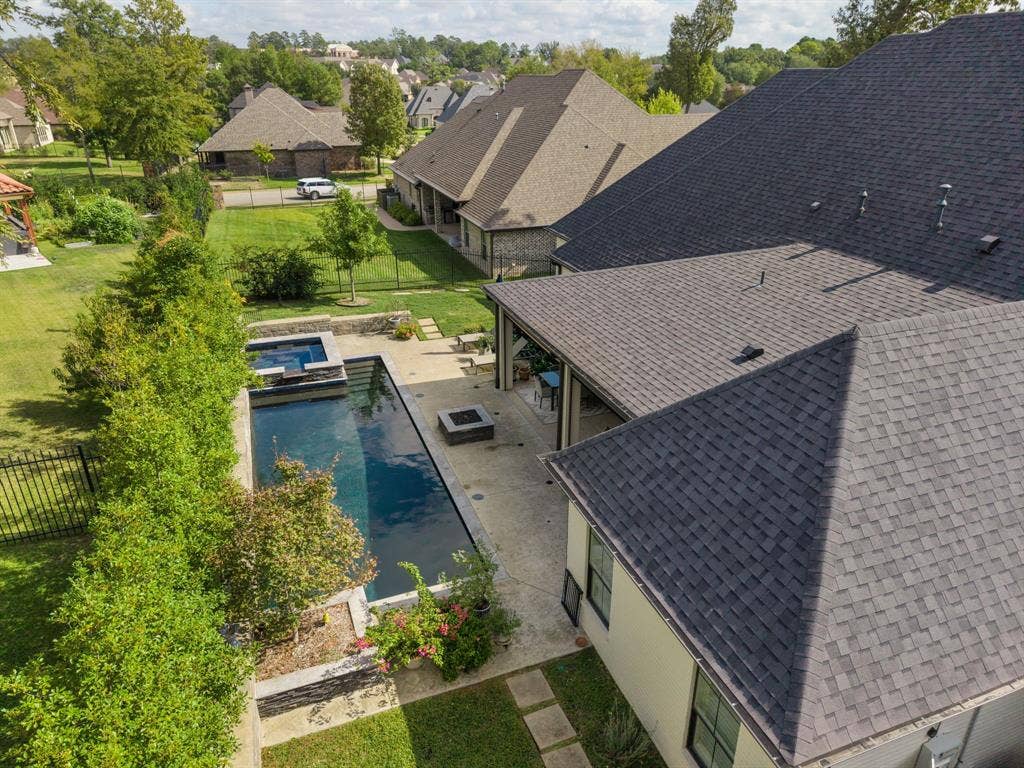 7609 Timber Trail, Tyler, TX 75703 Exterior backyard featuring a rectangular swimming pool, raised spa with stone veneer, covered patio, integrated fire pit, and professional landscaping