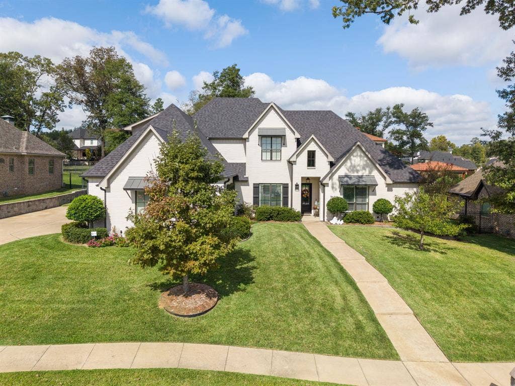 7609 Timber Trail, Tyler, TX 75703 Two-story brick exterior featuring a multi-gabled roofline, architectural asphalt shingles, dark metal window awnings, and a manicured lawn with mature landscaping