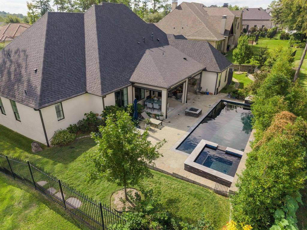 7609 Timber Trail, Tyler, TX 75703 Backyard featuring a rectangular swimming pool, an integrated spa, a paved stone patio, and a fenced-in lawn area