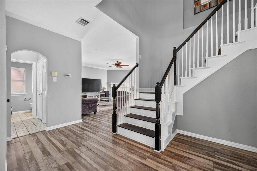 5726 Remington Drive, Garland, TX 75044 Entryway featuring wood-finish flooring, vaulted ceilings, and a staircase with white balusters and dark wood-finish treads