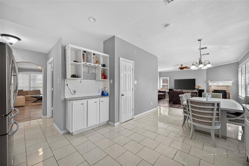 5726 Remington Drive, Garland, TX 75044 Built-in wet bar featuring white cabinetry, subway tile backsplash, and stone countertop, complemented by large-format tile flooring and recessed lighting