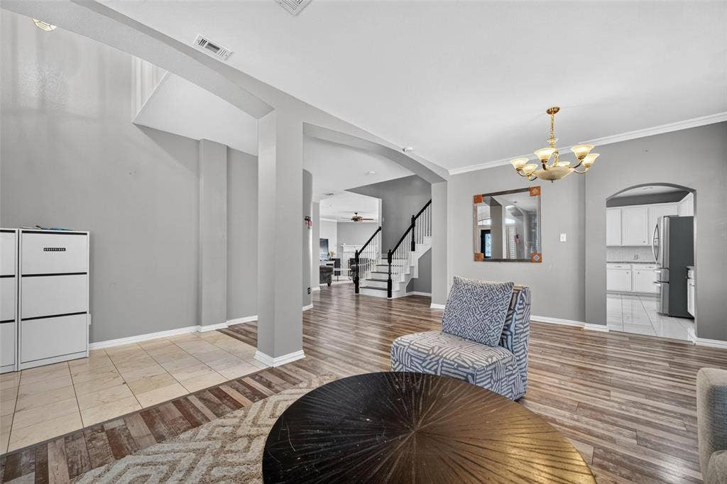 5726 Remington Drive, Garland, TX 75044 Open-concept interior featuring wood-finish flooring, tile accent flooring, archway architectural detailing, and a multi-arm chandelier