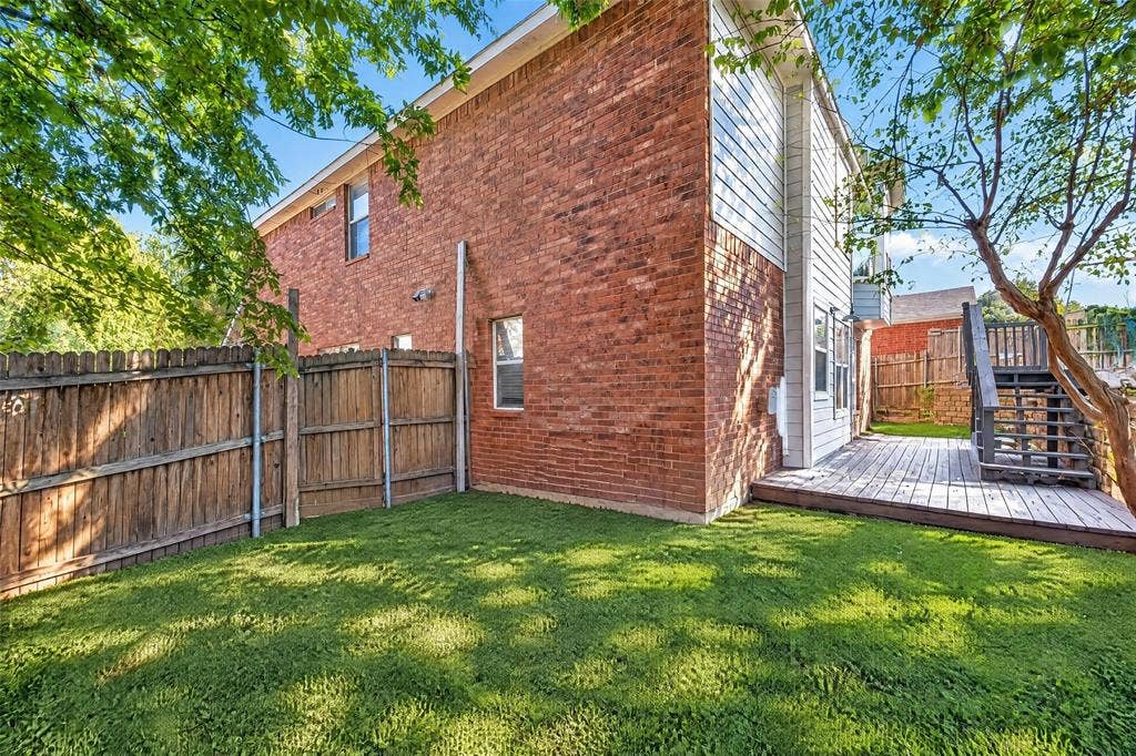 5726 Remington Drive, Garland, TX 75044 Exterior featuring red brick masonry, horizontal siding, wood-finish deck, and wood privacy fencing