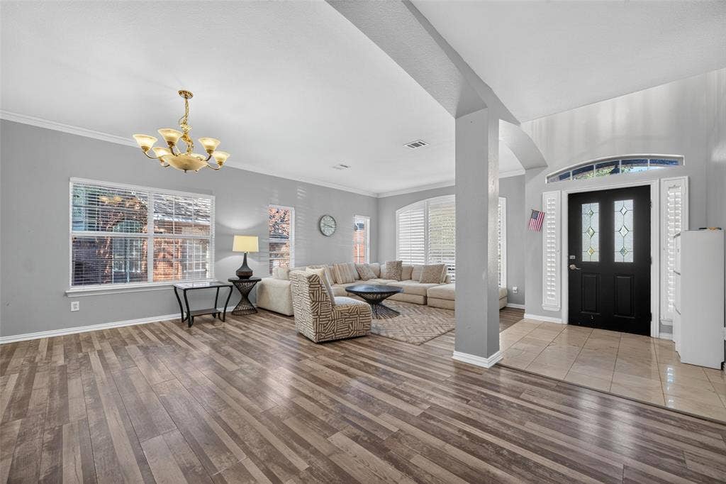 5726 Remington Drive, Garland, TX 75044 Open-concept interior featuring wood-finish flooring, a neutral color palette, arched architectural detailing, a multi-pane front door with a transom window, and a decorative ceiling-mounted chandelier