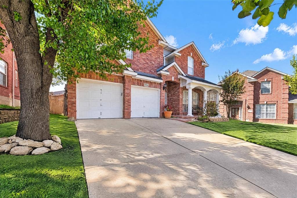 5726 Remington Drive, Garland, TX 75044 Two-story brick exterior featuring a covered front porch with columns, a two-car garage, and a concrete driveway