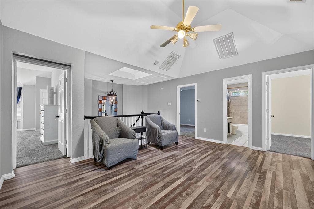 5726 Remington Drive, Garland, TX 75044 Vaulted ceiling featuring a skylight, wood-finish flooring, and a ceiling-mounted light fixture with a fan