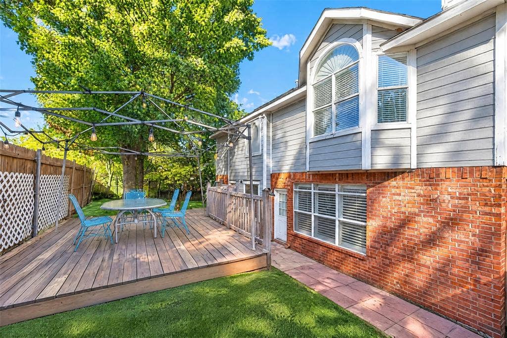 5726 Remington Drive, Garland, TX 75044 Multi-level exterior featuring a brick and horizontal siding facade, elevated wood deck, metal lattice pergola, and a stone-paver walkway