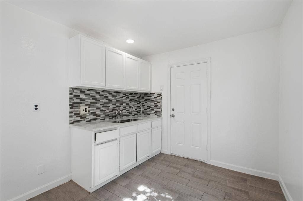 336 Bonnie View Road, Dallas, TX 75203 White cabinetry with stone-finish countertops, multi-tonal linear tile backsplash, stainless steel sink, and wood-finish flooring