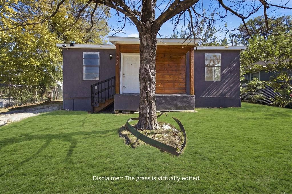 336 Bonnie View Road, Dallas, TX 75203 Exterior facade featuring dark-toned siding, a natural wood-finish porch accent, a metal staircase with railings, and dual-pane windows
