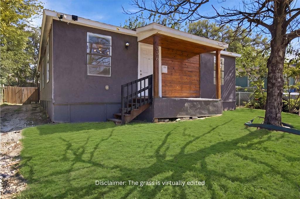 336 Bonnie View Road, Dallas, TX 75203 Exterior featuring stucco siding, a covered porch with wood-plank wall cladding, and a wood staircase with black metal railings