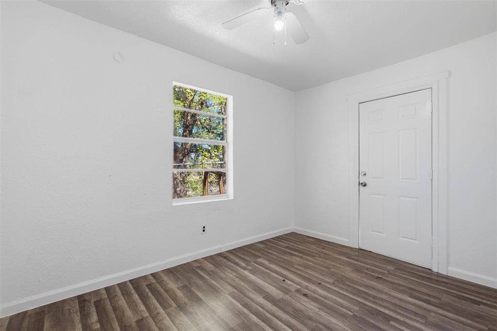336 Bonnie View Road, Dallas, TX 75203 Neutral-toned room featuring wood-finish flooring, a six-panel door, and a ceiling-mounted light fixture with an integrated fan