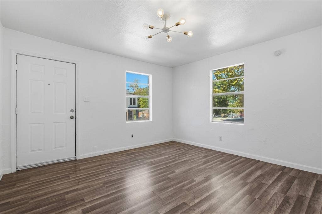 336 Bonnie View Road, Dallas, TX 75203 Interior space featuring wood-finish flooring, two dual-pane windows, a six-light sputnik-style ceiling fixture, and a white paneled entry door