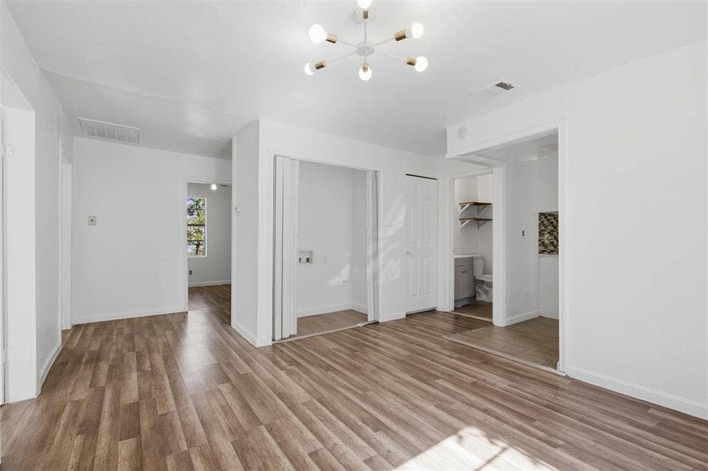 336 Bonnie View Road, Dallas, TX 75203 Wood-finish flooring, modern multi-arm light fixture, and dedicated laundry area with bifold doors