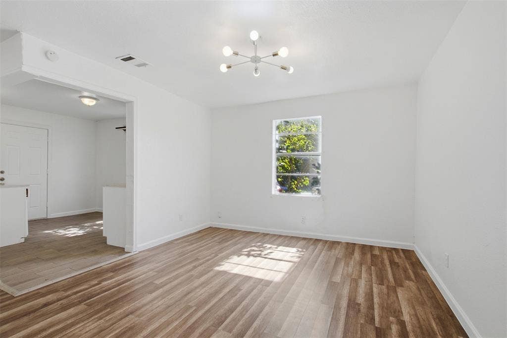 336 Bonnie View Road, Dallas, TX 75203 Neutral-toned interior featuring wood-finish flooring, a contemporary six-arm chandelier, and natural light from a double-hung window